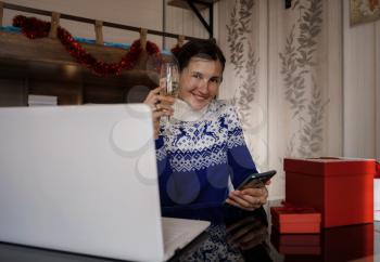 Happy asian woman wearing blue sweater holding glass of champagne, talking with family, social distance friend by video conference call meeting chat at home. stay home vocation, Christmas party online