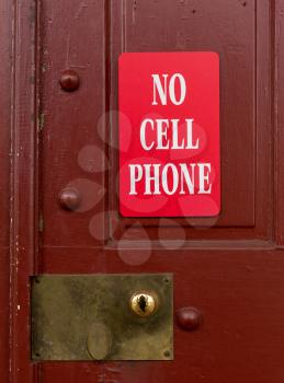Sign on red painted door warning that no cellphone or wireless phone usage is allowed