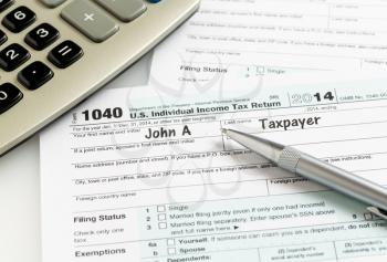 USA tax form 1040 for year 2014 with a pen and calculator illustrating completion of tax forms for the IRS