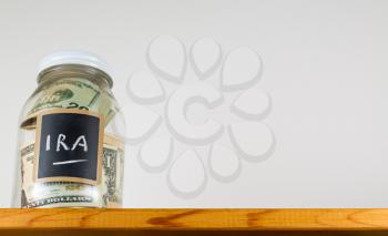 Single glass jar with chalk labels used for saving US dollar bills and notes for IRA retirement fund