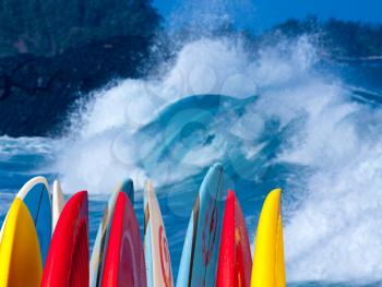 Dramatic powerful waves break over beach with stack of surfboards ready to go on beach at Lumaha'i, Kauai, Hawaii