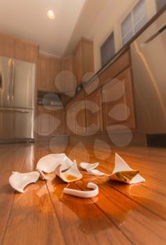 Concept of domestic disturbance at home with broken coffee cup on floor of modern kitchen