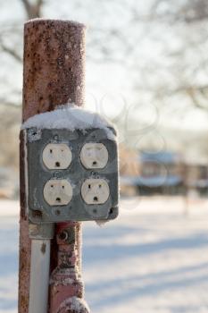 Snow covered electricity sockets or outlets that would not meet current building code requirements with snow filling the electrical connections