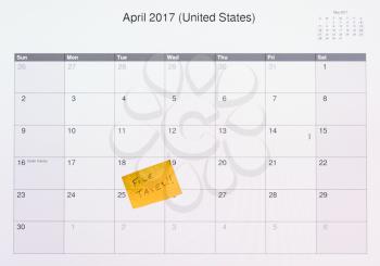 Yellow sticky note on computer screen of monitor showing calendar with the date of 18 April as the tax filing deadline in 2017