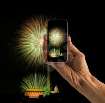 Tourist taking photo on smartphone of Washington DC firework display for Independence Day