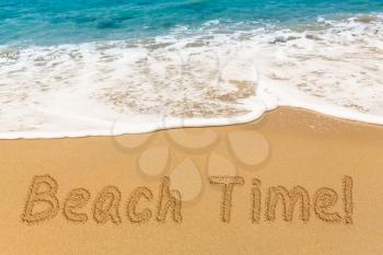 Beach Time words written into sand on beach by warm blue ocean in Caribbean advertizing vacations and holidays