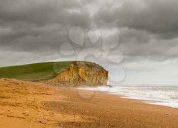 Cold sea surf on beach by Jurassic Coast cliffs and headland at West Bay in Dorset used as the location for the Broadchurch TV series
