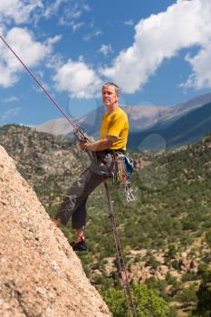 Senior male climber well equipped with cams and caribiners rappelling down Turtle Rocks near Buena Vista Colorado