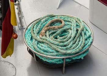 Coiled old and worn rope on deck of cruise boat ready to tie the ship at the next dock