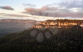 Rising sun illuminates clouds and mist in the valley from Sublime Point overlooking the majestic Blue Mountains near Sydney NSW Australia
