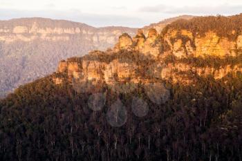 Rising sun illuminates Three Sisters in the valley from Sublime Point overlooking the majestic Blue Mountains near Sydney NSW Australia