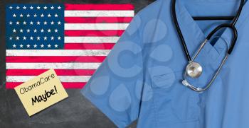 Blue doctor scrubs shirt and stethoscope hang empty in front of USA flag. Illustration of healthcare system problems with question about ObamaCare replacement