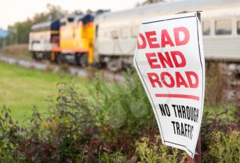 Dead End sign by railroad crossing with Diesel locomotive engine on steep trip into mountains of West Virginia