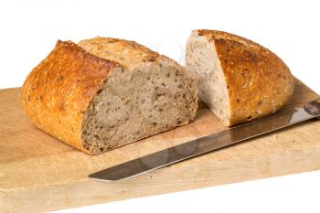 Whole wheat or multi grain brown bread fresh from oven bakery placed on wooden breadboard with knife and isolated against a white background