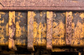Detail of rust and remaining yellow paint on heavy yellow industrial truck and equipment abandoned in economic recession