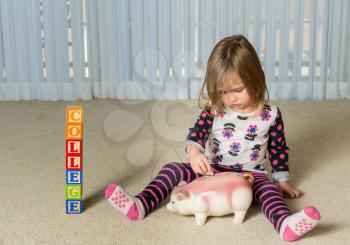 Young girl on floor of home saving money in a piggy bank for college educational expenses in the future