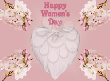 Happy Women's Day or International Womens Day celebrated on March 8th. Pink background image with white embroidered heart surrounded by cherry blossoms