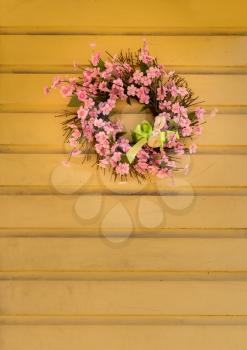 Pink wreath with flowers and ribbon and small bunny rabbit shape for easter celebrations