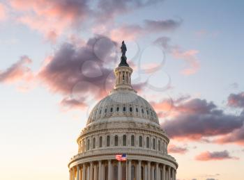 US flag flies in front of the US Capitol in Washington DC as the sun rises at dawn on a new day