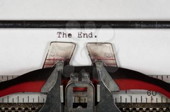 Macro detail of the ink ribbon and text of The End on electric typewriter for newspaper media