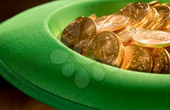 Treasure of pure gold eagle coins inside the rim of a green velvet hat to celebrate luck on St Patrick's Day of March 17th