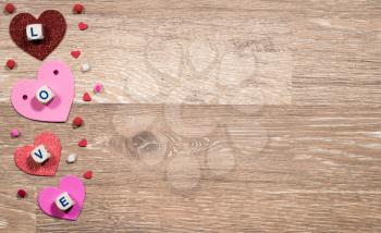 Love spelled in wooden blocks with heart shaped cutouts for Valentines day on wooden floor with copy space