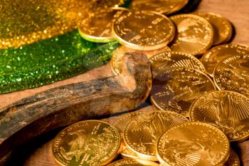 Treasure of pure gold coins from a green hat on rustic wooden table into horseshoe to celebrate luck on St Patrick's Day