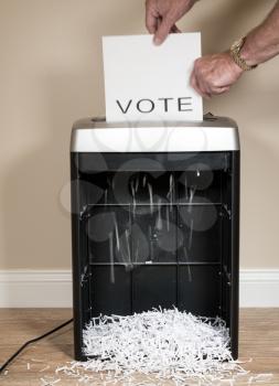 Simple paper vote being shredded as a wasted vote in an office shredder