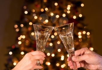 Caucasian senior married couple clink crystal champagne glasses against defocused xmas tree lights