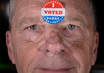 I Voted Today sticker on senior caucasian mans forehead with warm smiling look at camera