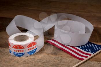 Large roll of I Voted Today stickers with many having been used for voters in the US elections with USA flag on table