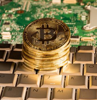 Bitcoin coin on a keyboard with computer board to illustrate blockchain and cyber currency