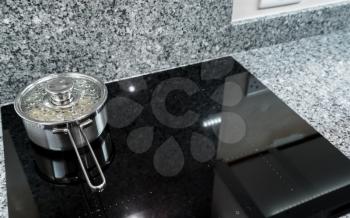 Water and potatoes boiling in stainless steel pan on modern induction hob or cooktop