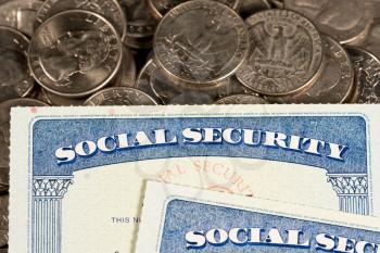 USA Social security cards laid on pile of quarter coins to illustrate money in retirement