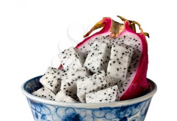 Dragon fruit cut in half with distinctive red skin in a blue pottery bowl isolated against a white background