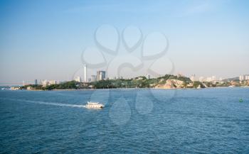 Ferry boat passes island of Gulangyu in foreground with background of Xiamen in China
