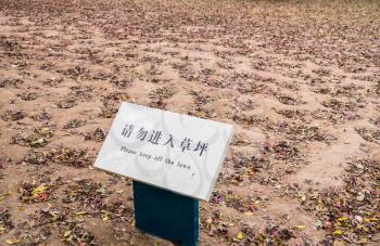 Funny message to keep off lawn in middle of bare dirt and soil
