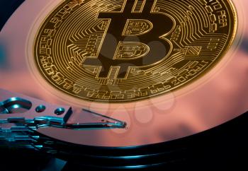 Bitcoin superimposed on the discs of a hard drive storage to illustrate bitcoin mining