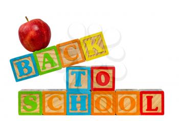 Stack of wooden blocks stacked to spell Back to School with red apple on top against white background