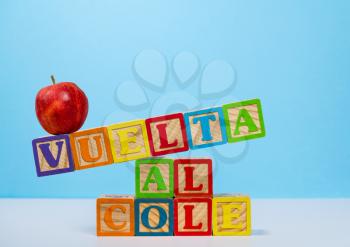 Vuelta al Cole translates to Back to School in spanish with wooden blocks with red apple on top