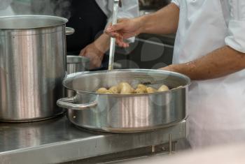Chef preparing food  in commercial stainless steel kitchen in restaurant