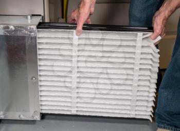 Senior caucasian man changing a folded air filter in the HVAC furnace system in basement of home