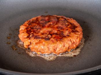 Charred and ready to eat plant-based burger in frying pan