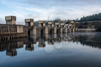 Solid structure of the Crestuma Lever dam on River Douro in Portugal reflected in calm water