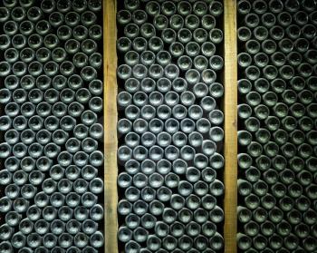 Stacks of wine bottles laying flat in wooden racks in old wine cellar or cave