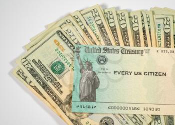 Stack of 20 dollar bills with US Treasure illustrative check to illustrate coronavirus stimulus payment on white background