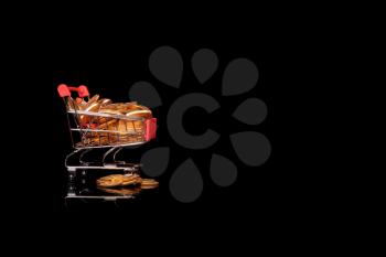 Mockup or concept background for winter sales with shopping cart filled with gold coins set against a black background