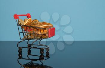 Mockup or concept background for winter sales with shopping cart filled with gold coins set against a blue background