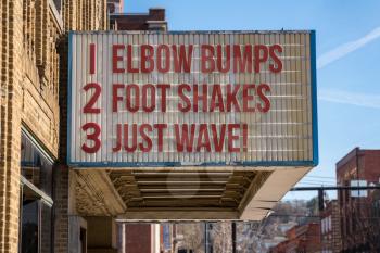 Movie cinema billboard with three rules to replace handshakes with elbow bumps, footshakes or just waving to friend during coronavirus epidemic