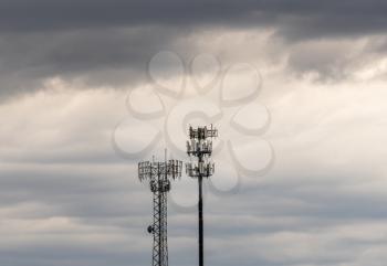 Two towers providing cellular broadband and data service to rural areas on stormy day. Illustrates digital divide.